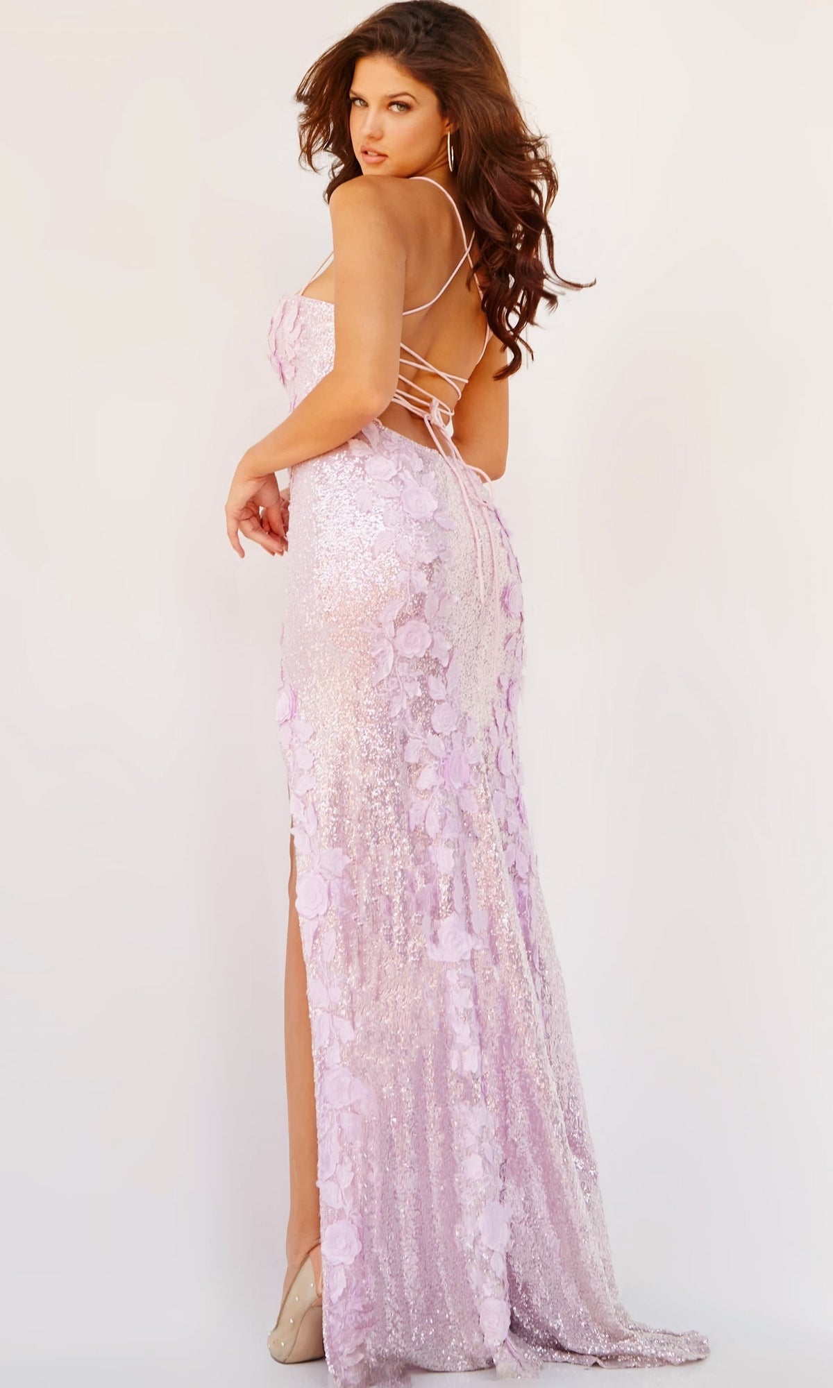 Woman in the Jovani 06109 Sequin-Print Long Prom Dress featuring light purple sequins, floral detailing, thin straps, and a lace-up back—styled with heels for a glamorous formal look.
